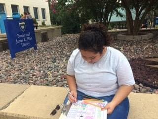 Paola Estrada Amaya colors outside the Library on Thursday. 
Photo by Heather Birge. 