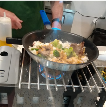 An Aramark employee uses a stir-fry pan to create customized bowls at Chopsticks Modern Stir-Fry. 