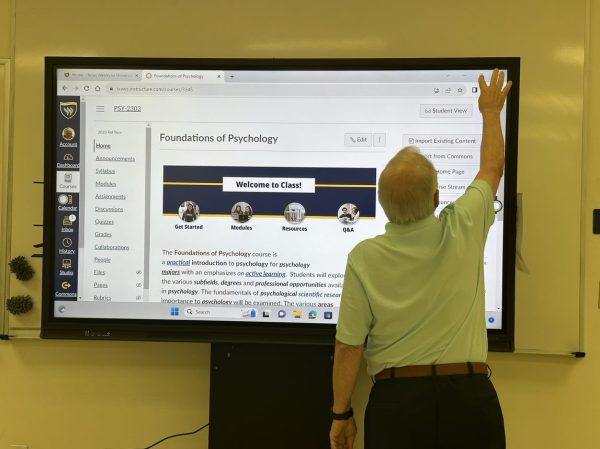 Dr.  Alan Henderson of Psychology uses the smart TV to get ready for class.