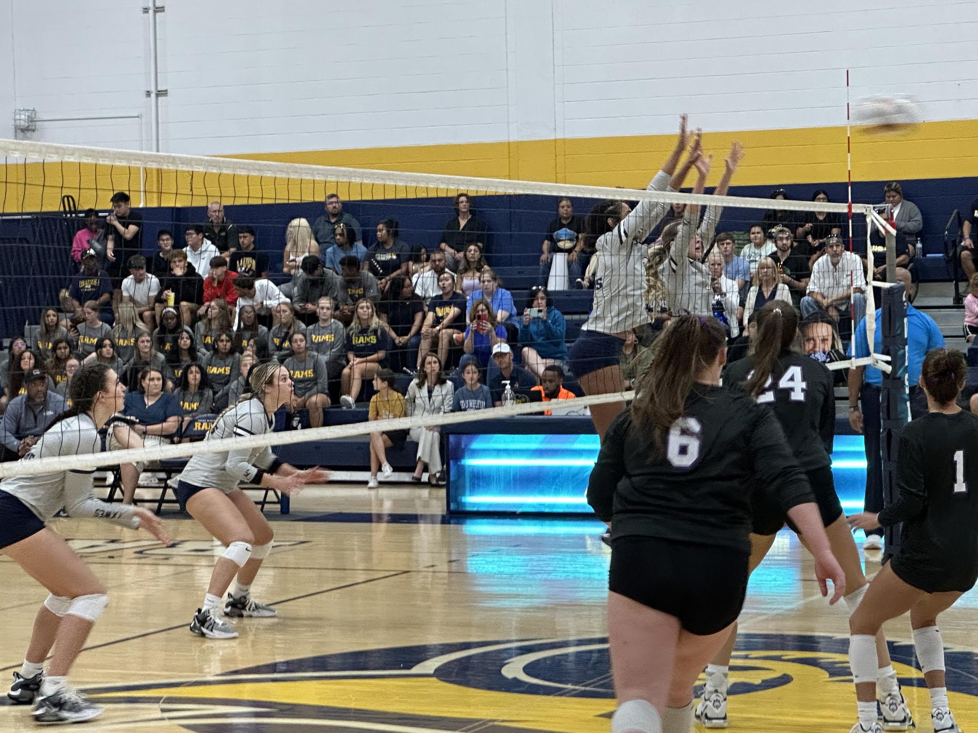 The Lady Rams block the net from a spike. 
