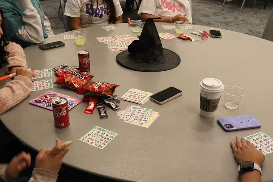 The Alpha Xi Delta sorority provides bingo cards and markers during their bingo night. A table of members calls out numbers and then players mark their card looking to create an X pattern. 