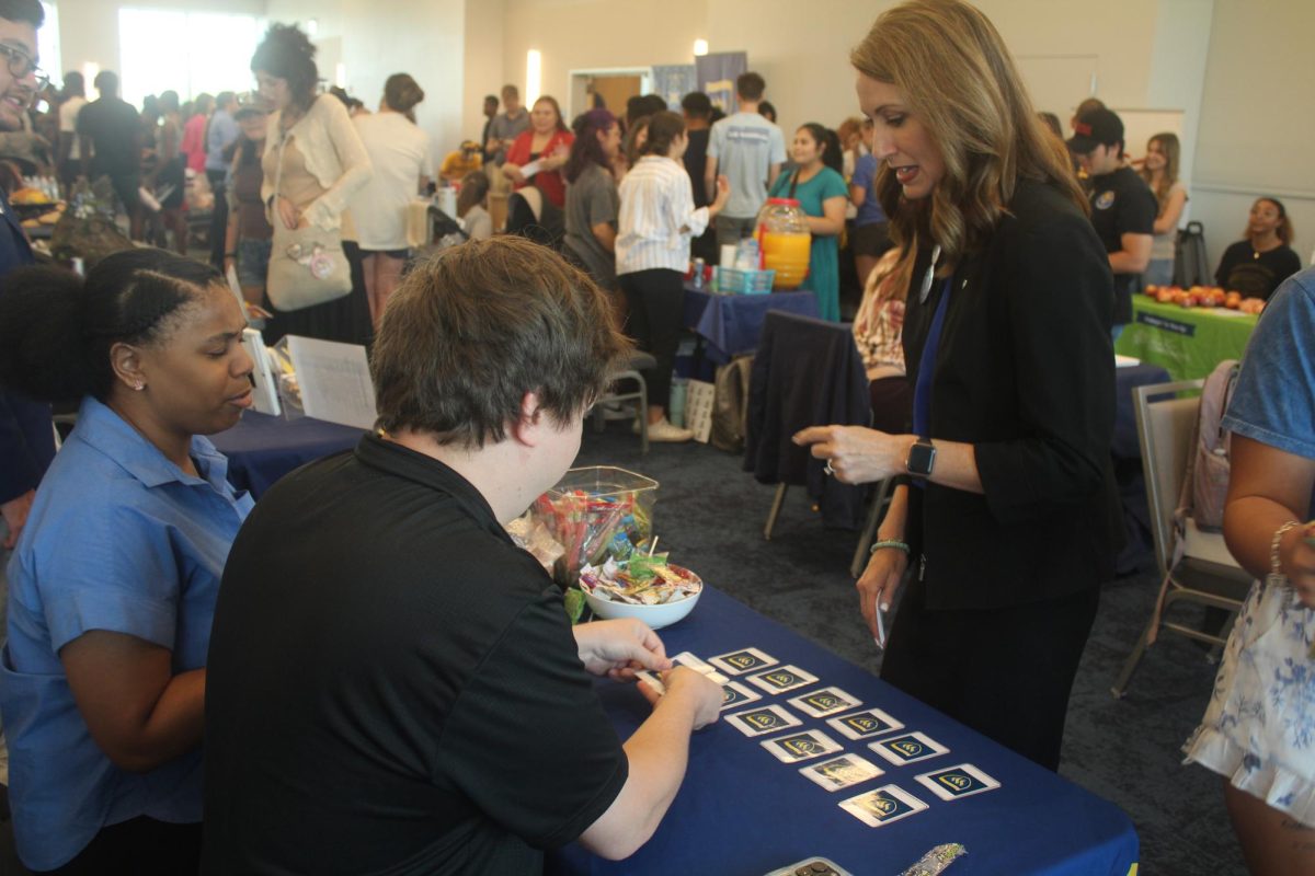 Residence Life Coordinator Grady Rogers sets up a game of memory match with Wesleyan themed cards for President Emily Messer for the TxWes housing table. 