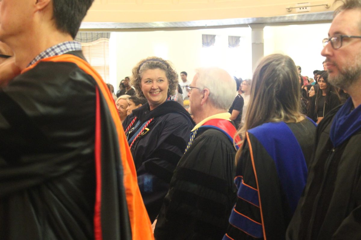 Two faculty members share a laugh during procession.