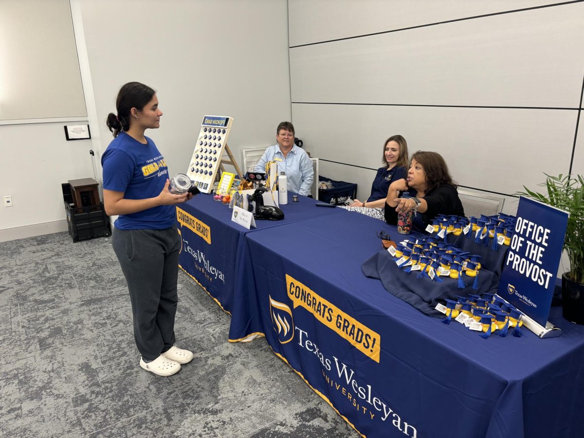 Members of the Provost Office, Tammy Titlow (left), Ashley Babb, and Cynthia Cedillo, assist fall 2024 graduates by directing them to office representatives who are there to help them.