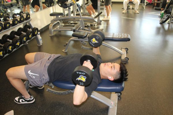 Sophomore finance major Thiago Uieda presses the new dumbbells in the Morton Fitness Center.